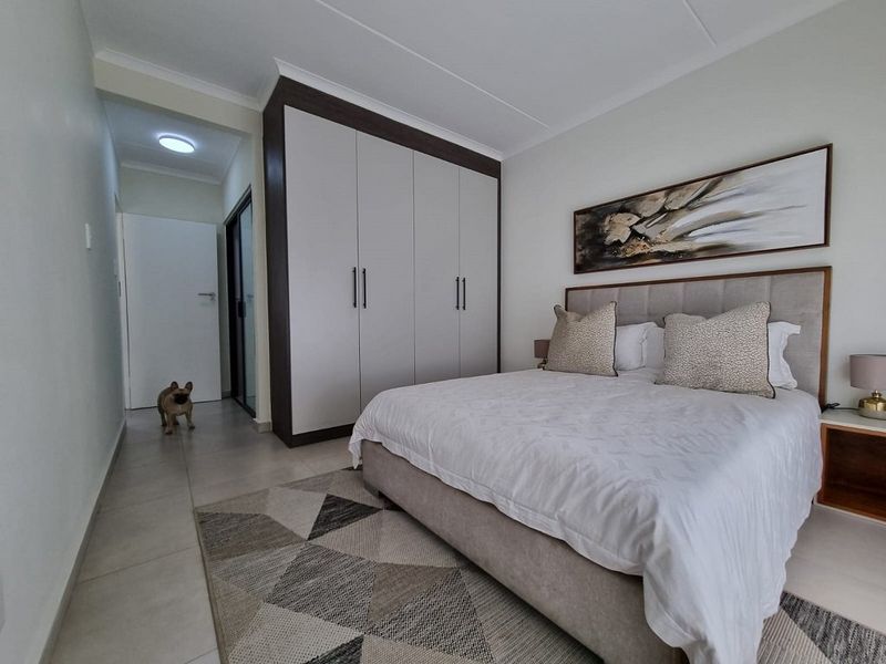 A well-maintained bedroom featuring neutral tiled flooring, a modern built-in wardrobe with dark trim, and clean finishes.