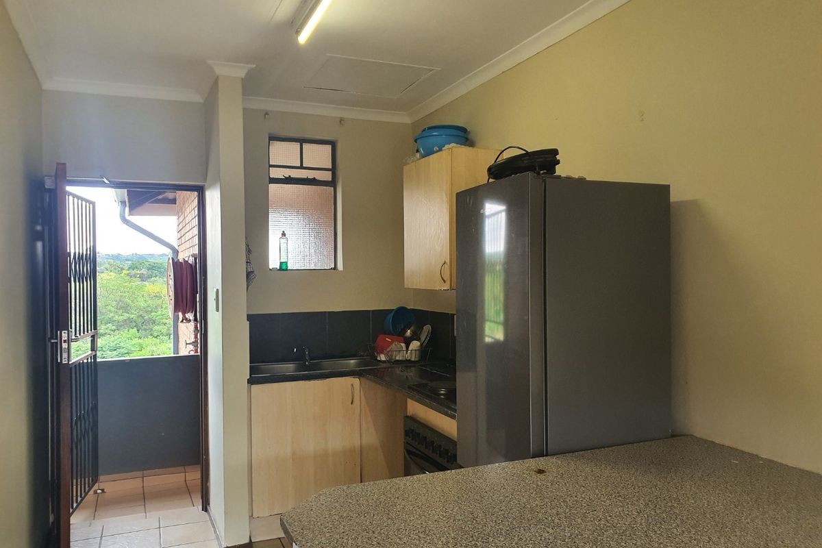 Compact kitchen featuring built-in cabinetry, laminate countertops, and a tiled backsplash, with direct access to an outdoor balcony area.