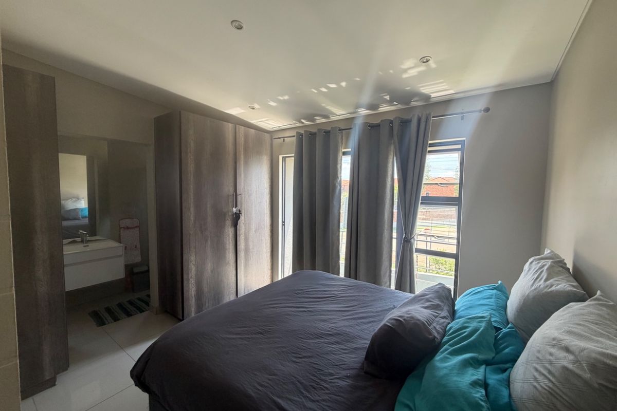 A well-lit bedroom featuring built-in cupboards, tiled flooring, and recessed downlights, offering a clean and functional living space.