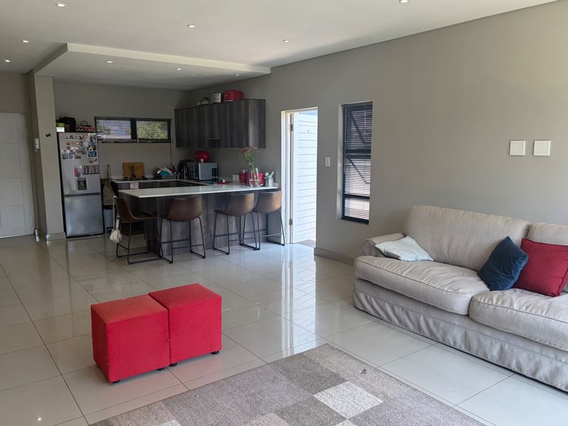 Open-plan living area featuring a modern kitchen with a central island, stone countertops, and tiled flooring throughout, creating a seamless flow.