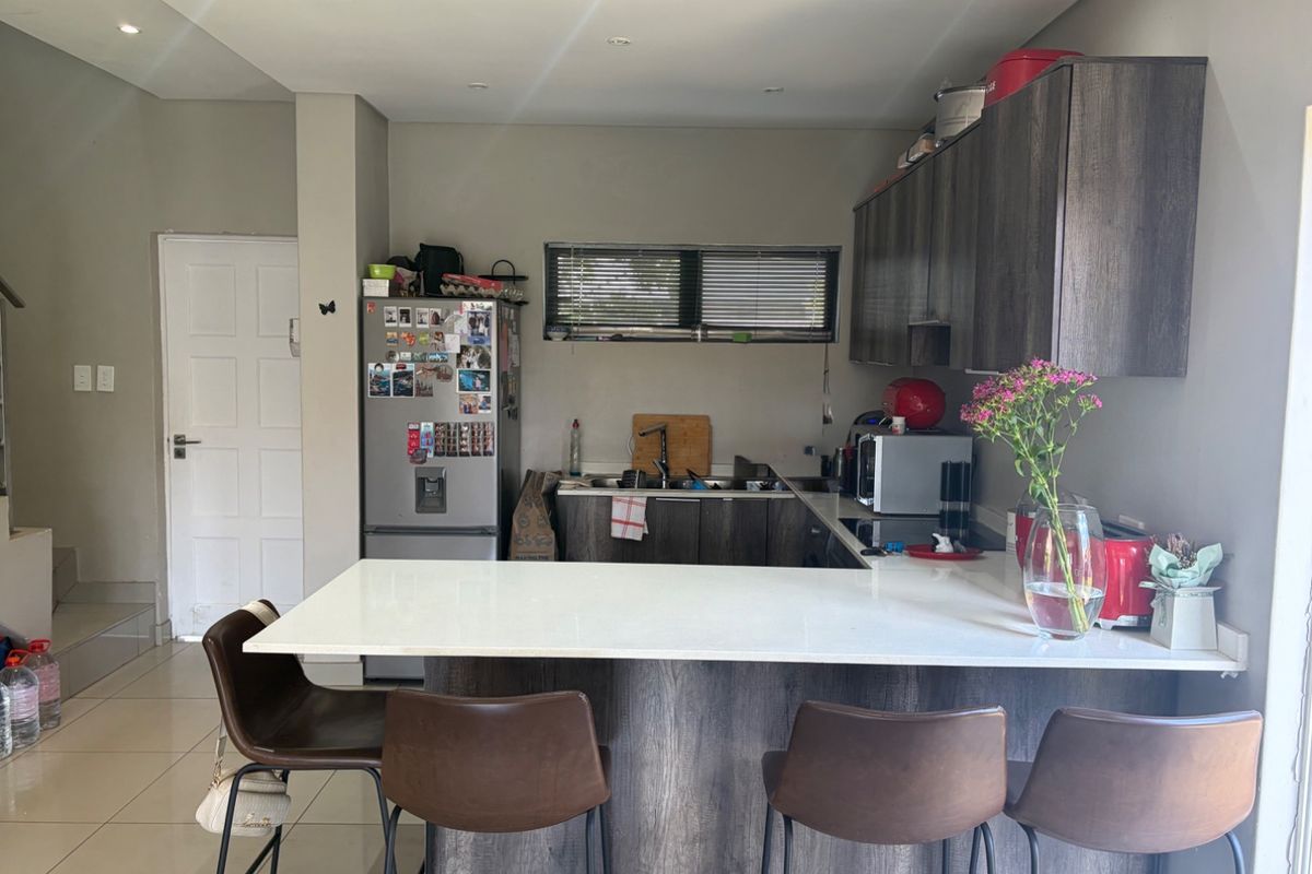 A functional kitchen featuring dark wood-look cabinetry, a white stone breakfast bar, and tiled flooring, providing a practical and modern cooking space.
