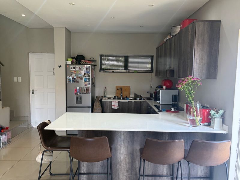 A functional kitchen featuring dark wood-look cabinetry, a white stone breakfast bar, and tiled flooring, providing a practical and modern cooking space.