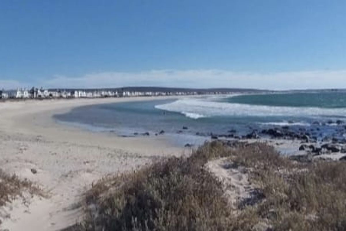 A scenic view of the coastal landscape featuring a sandy beach and ocean frontage, highlighting the property's prime location.
