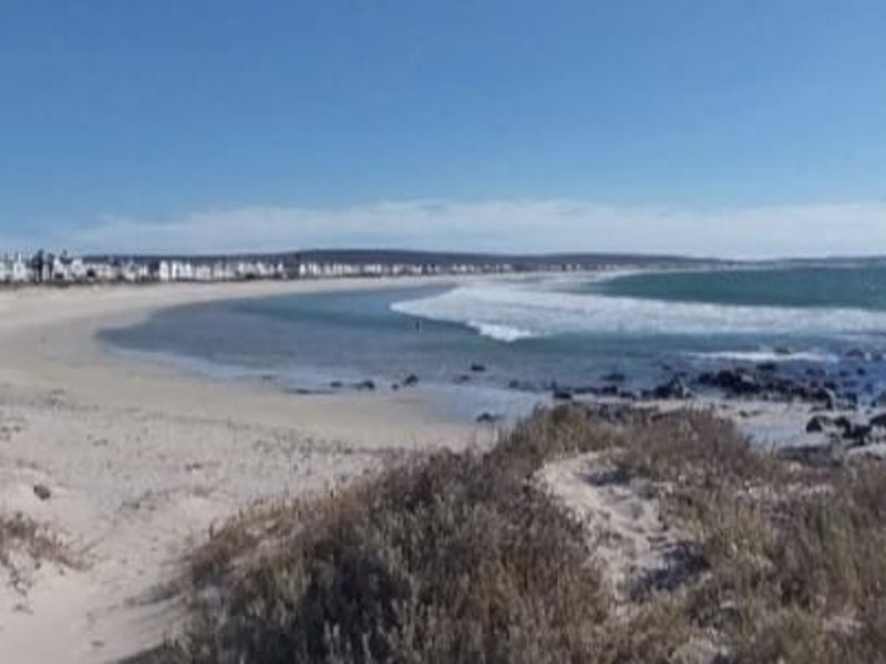 A scenic view of the coastal landscape featuring a sandy beach and ocean frontage, highlighting the property's prime location.