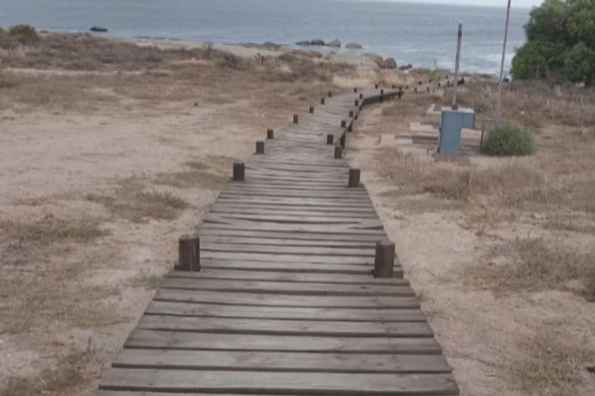 A wooden boardwalk path leading towards the coastline, providing direct access to the beach area.