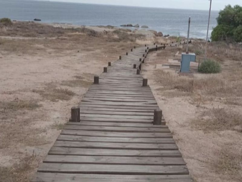 A wooden boardwalk path leading towards the coastline, providing direct access to the beach area.