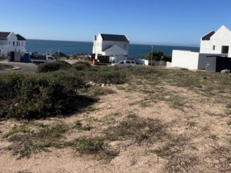 A vacant residential plot situated in a coastal neighborhood, offering potential for development with surrounding established homes and ocean views.