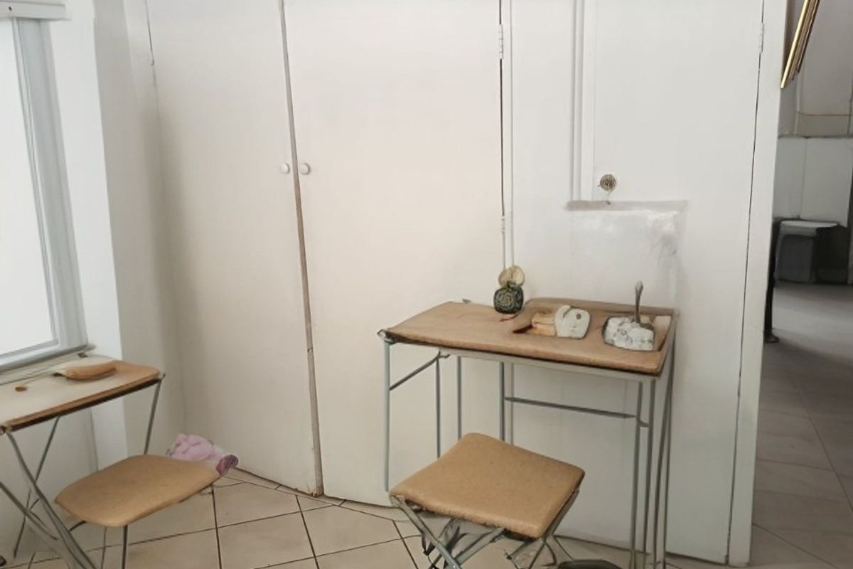 A bedroom featuring tiled flooring and a built-in cupboard, currently used as a workspace.