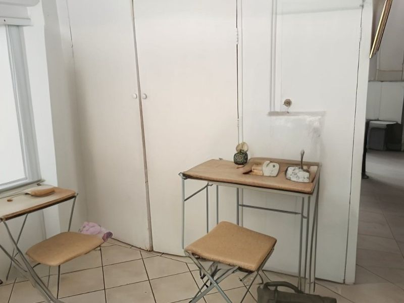 A bedroom featuring tiled flooring and a built-in cupboard, currently used as a workspace.