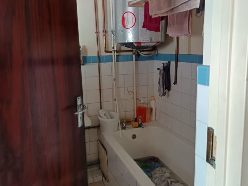 A functional bathroom featuring a bathtub and an exposed electric water heater system with tiled walls and flooring.