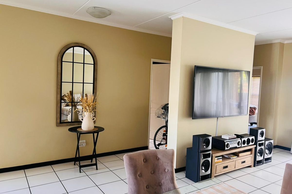 A living room area featuring tiled flooring and a coved ceiling, providing a functional space with a central partition wall.