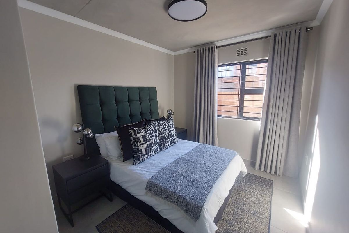 A well-maintained bedroom featuring tiled flooring, a coved ceiling, and a window fitted with security bars, providing a clean and functional living space.
