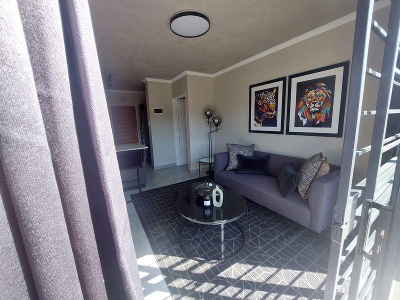A well-maintained living room featuring neutral wall tones, tiled flooring, and a modern flush mount ceiling light, creating a comfortable and inviting atmosphere.