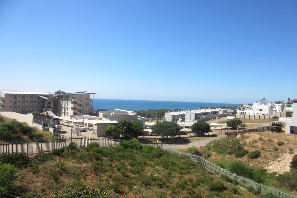 A wide-angle view of the surrounding coastal landscape and residential neighborhood, showcasing the property's elevated position and proximity to the ocean.