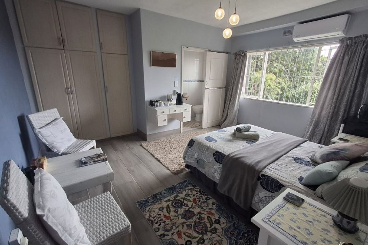 Spacious bedroom featuring built-in cupboards, tiled flooring, a split-system air conditioner, and direct access to an en-suite bathroom.