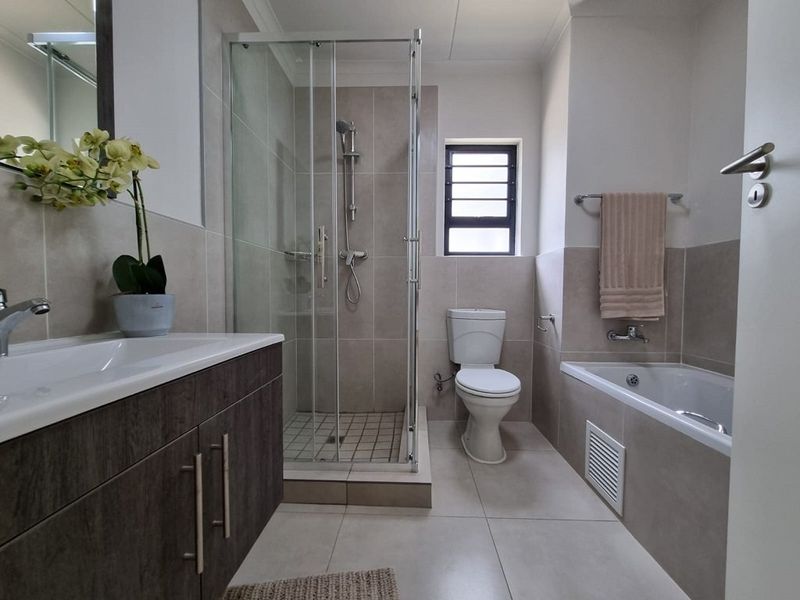 Modern bathroom featuring a vanity cabinet, separate shower enclosure, bathtub, and neutral tiled finishes throughout.