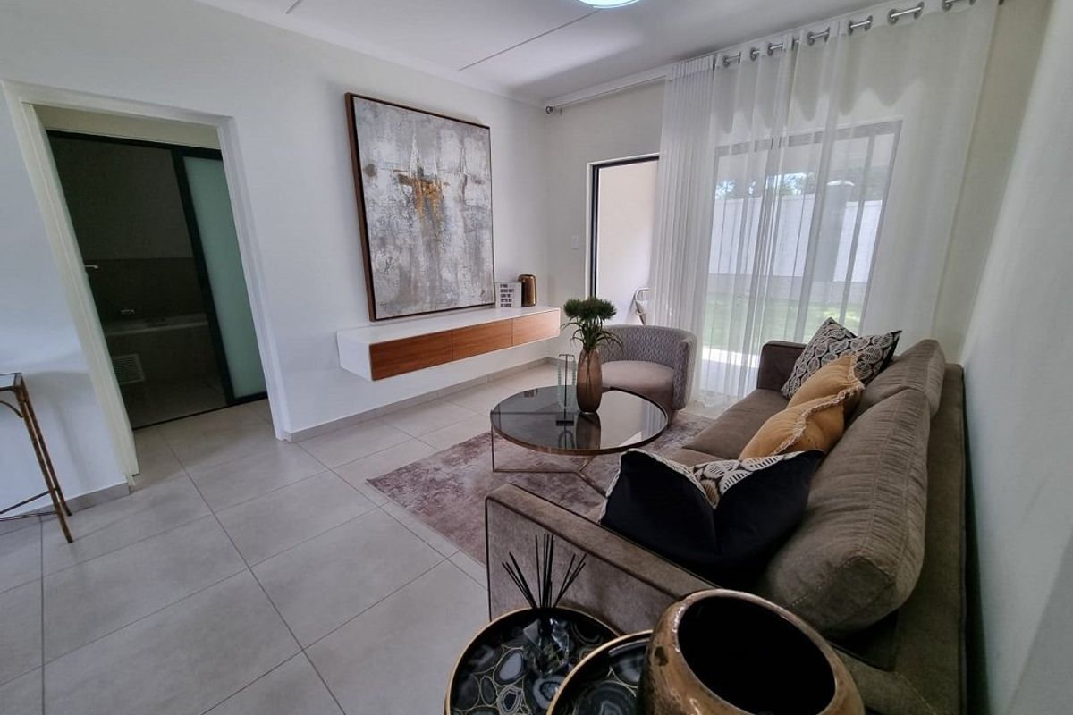 A bright and modern living room featuring tiled flooring, a floating media console, and a sliding glass door providing access to the outdoor area.