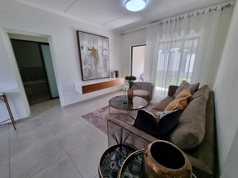 A bright and modern living room featuring tiled flooring, a floating media console, and a sliding glass door providing access to the outdoor area.