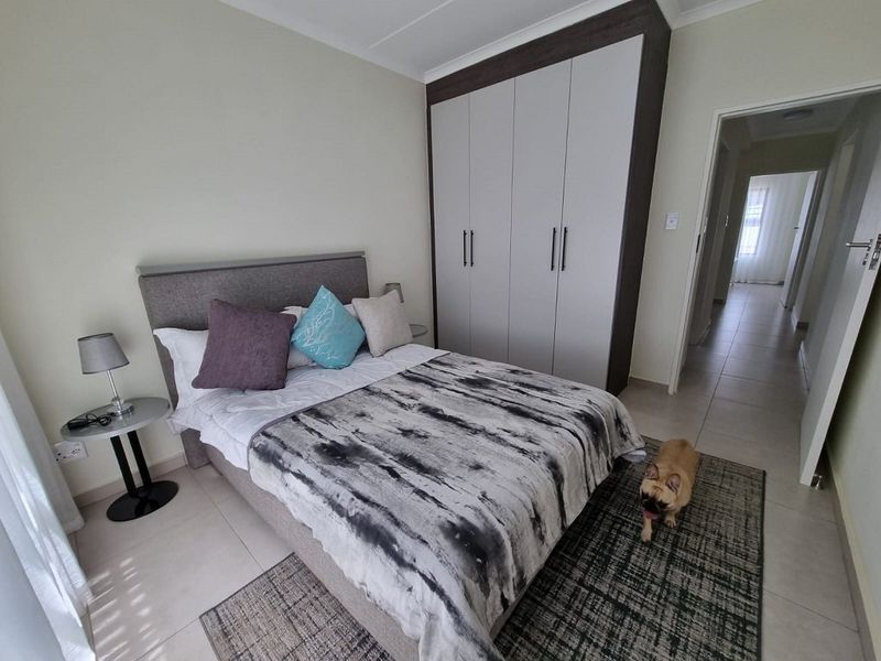 A well-maintained bedroom featuring neutral tiled flooring and a modern built-in wardrobe with clean lines.