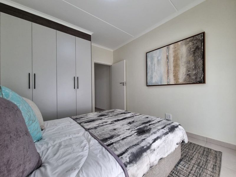 A well-maintained bedroom featuring neutral walls, tiled flooring, and modern built-in cupboards with dark trim detailing.