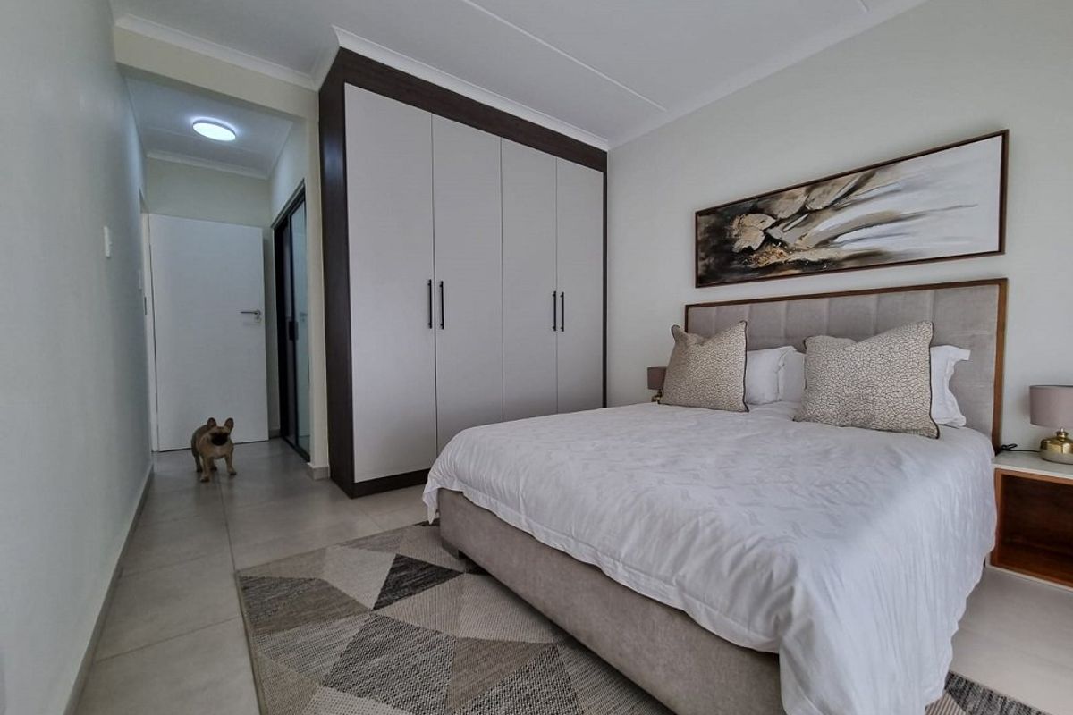 A well-maintained bedroom featuring neutral tiled flooring, a modern built-in wardrobe with dark trim, and clean finishes.