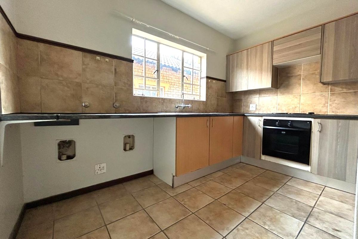 A functional kitchen featuring built-in cabinetry, an oven, and tiled finishes, currently awaiting updates to the cabinetry and plumbing fixtures.