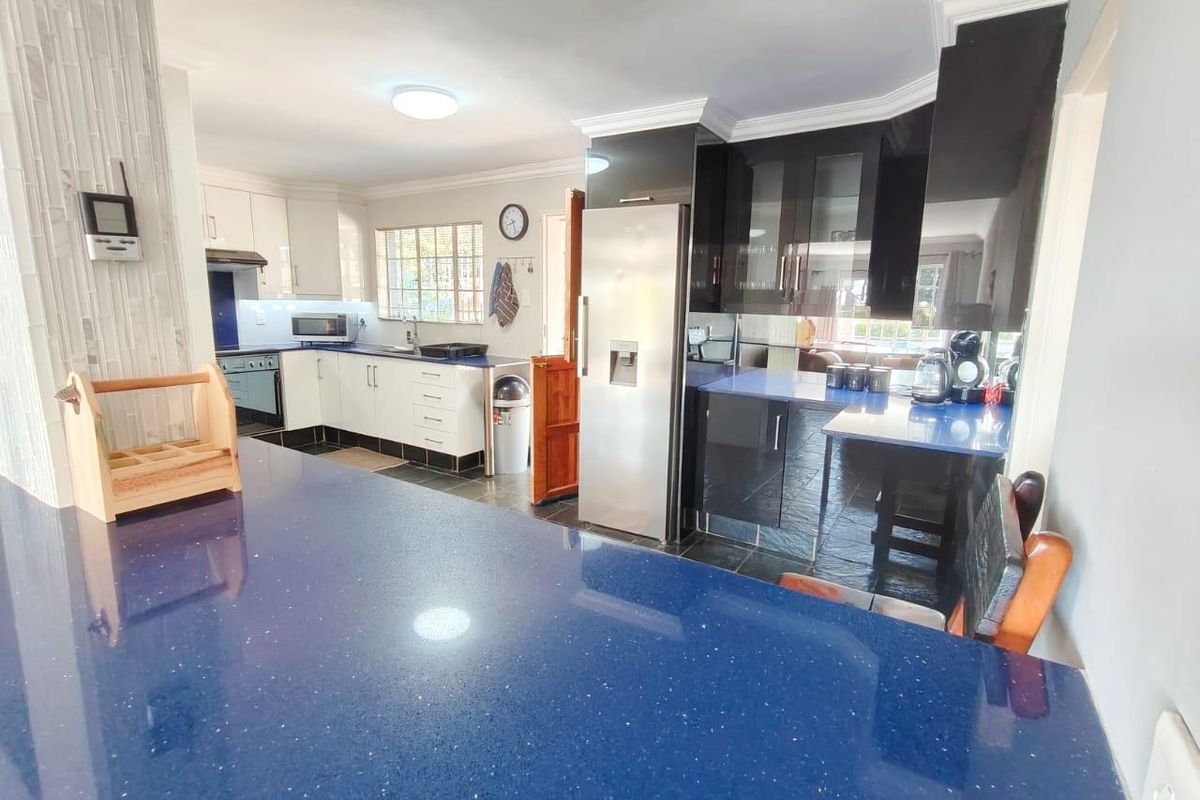 Modern kitchen featuring high-gloss cabinetry, striking blue stone countertops, integrated appliances, and tiled flooring, offering a functional and stylish culinary workspace.