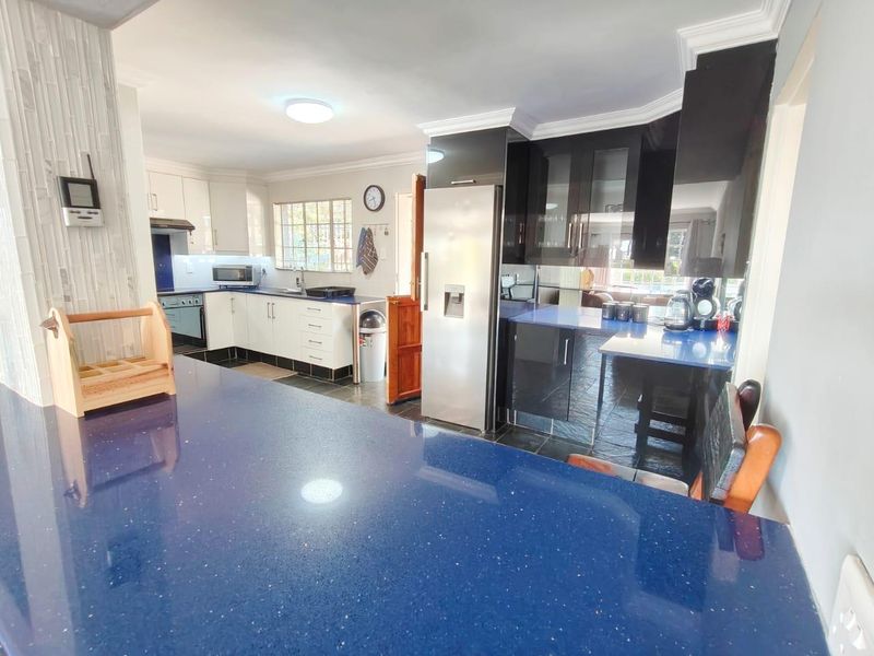Modern kitchen featuring high-gloss cabinetry, striking blue stone countertops, integrated appliances, and tiled flooring, offering a functional and stylish culinary workspace.