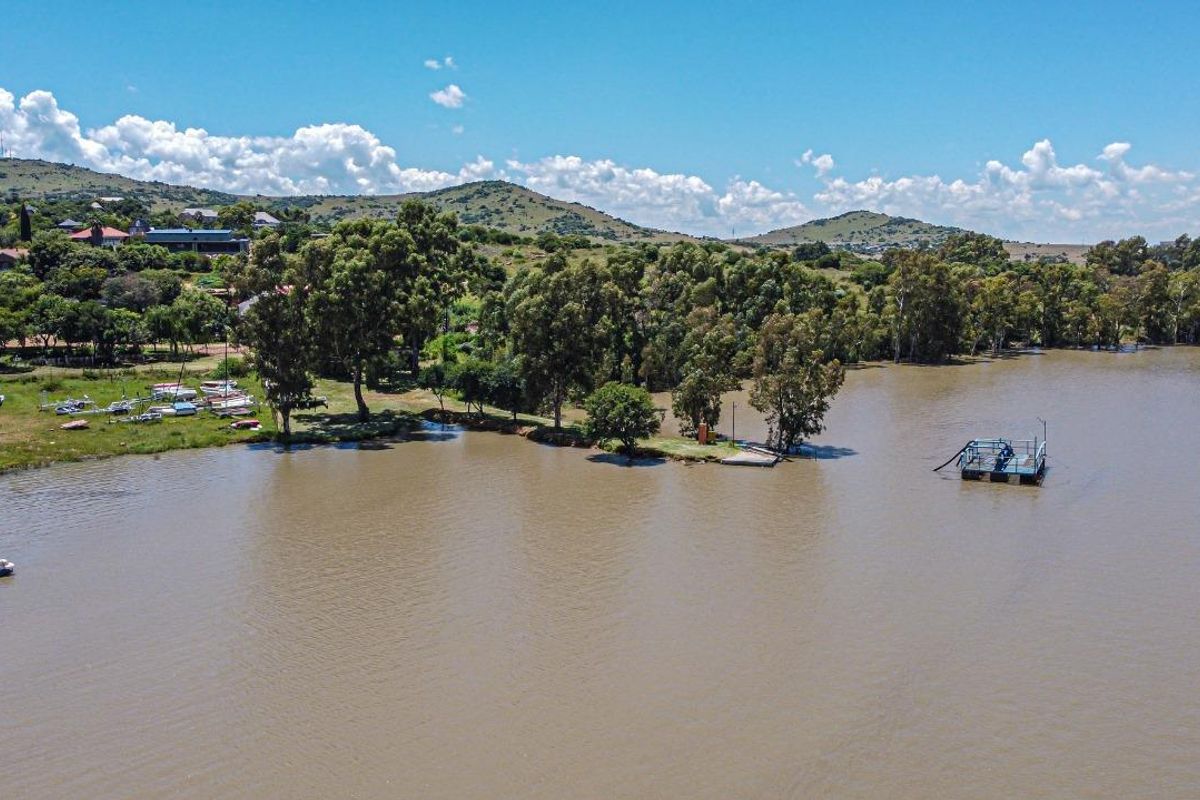 Aerial view of the property's waterfront location, featuring a natural lake, mature trees, and a private floating jetty.