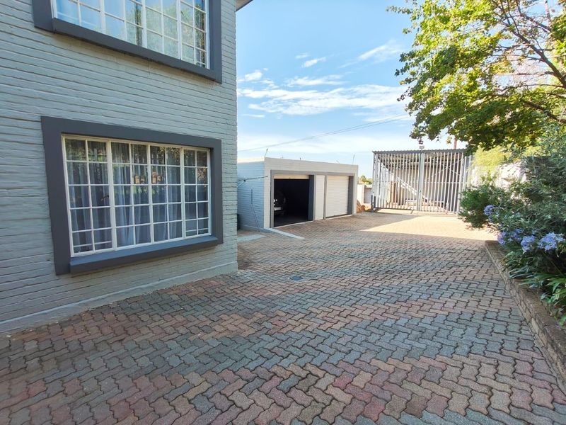 A well-maintained front exterior view featuring a paved driveway, double garage, and secure gated access to the property.