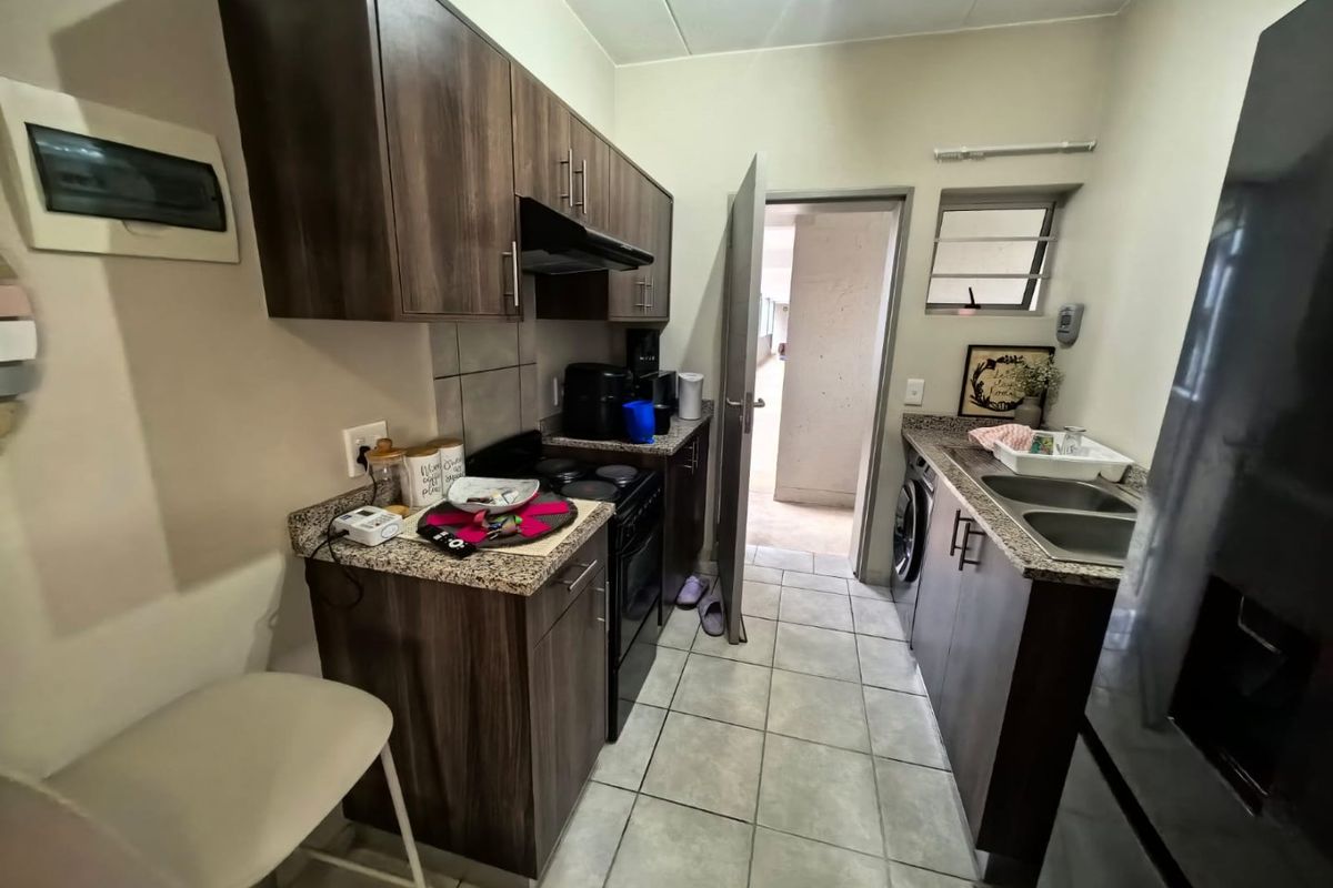 Compact kitchen featuring dark wood cabinetry, granite countertops, a double basin sink, and built-in electric stove with extractor fan.