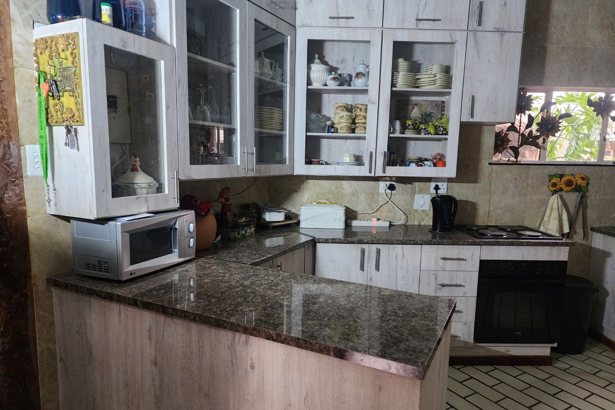 A functional kitchen featuring light wood-grain cabinetry, granite countertops, a built-in oven, and a tiled backsplash with ample storage space.
