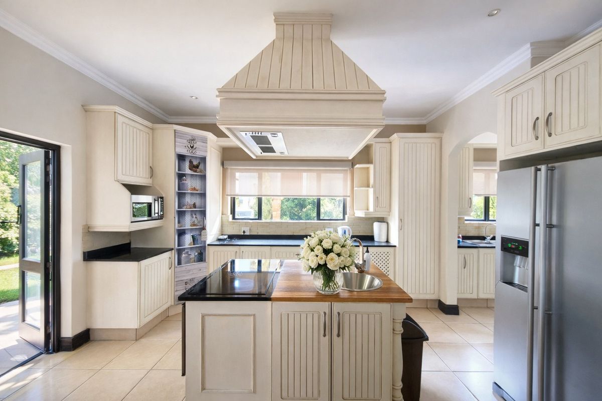 A well-appointed kitchen featuring a central island with a cooktop, ample cabinetry, integrated appliances, and direct access to the outdoor area.