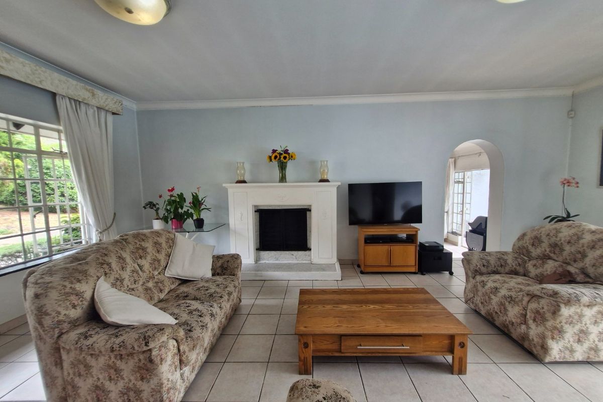 A spacious living room featuring a central fireplace, tiled flooring, and an arched entryway leading to an adjacent space.