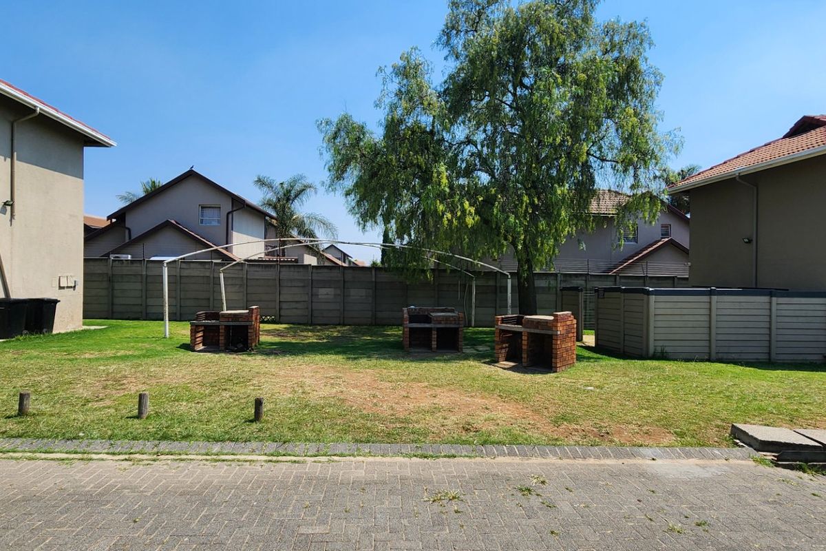 Communal outdoor area featuring brick braai stands, a lawn, and precast boundary walls between apartment buildings.