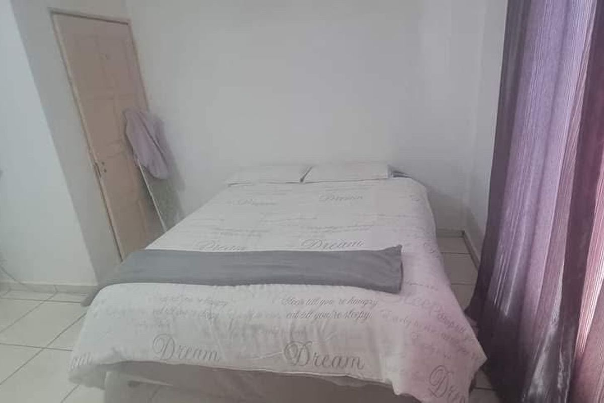 A simple bedroom featuring tiled flooring and neutral wall finishes, providing a functional space for rest.