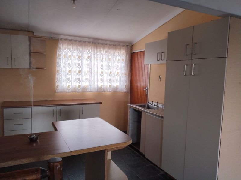 A dated kitchen featuring built-in cabinetry, laminate countertops, and a stainless steel sink, offering potential for a modern renovation.