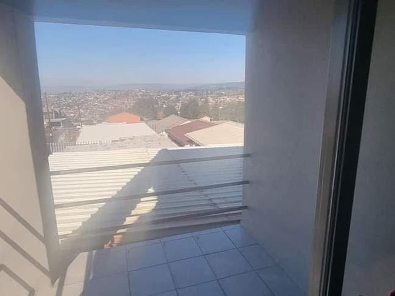 A covered balcony featuring tiled flooring and a metal balustrade, offering an elevated view of the surrounding neighborhood.