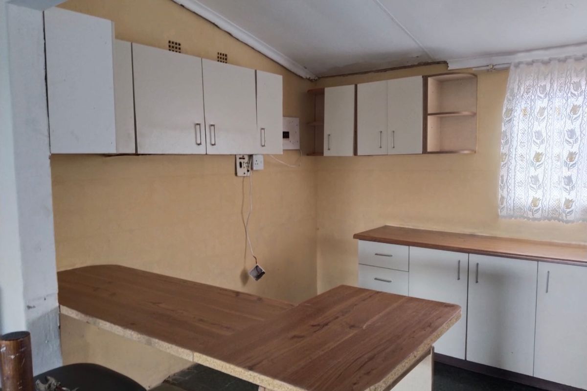 A functional kitchen space featuring laminate countertops, built-in cabinetry, and a breakfast bar, offering a blank canvas for potential renovation and modernization.