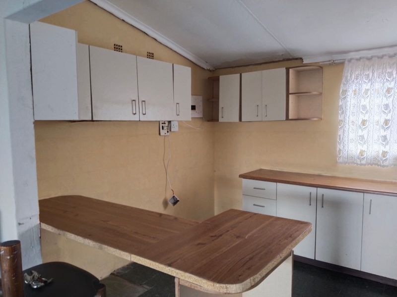 A functional kitchen space featuring laminate countertops, built-in cabinetry, and a breakfast bar, offering a blank canvas for potential renovation and modernization.