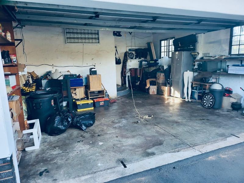 A spacious garage area featuring a concrete floor and functional garage door mechanism, offering ample storage potential for vehicles or workshop use.