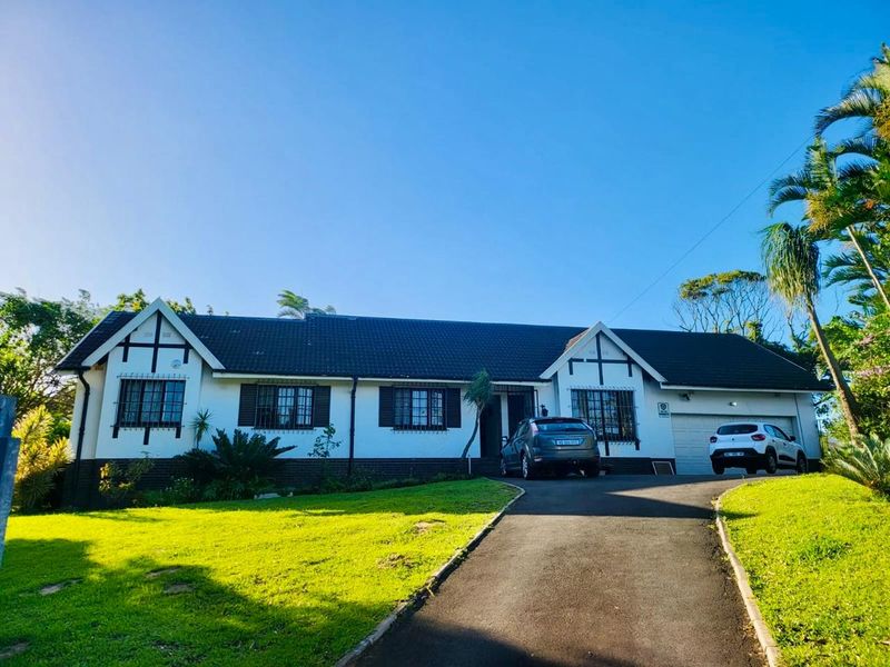 A well-maintained single-story house featuring a tiled roof, security bars on windows, and a paved driveway leading to an attached garage.