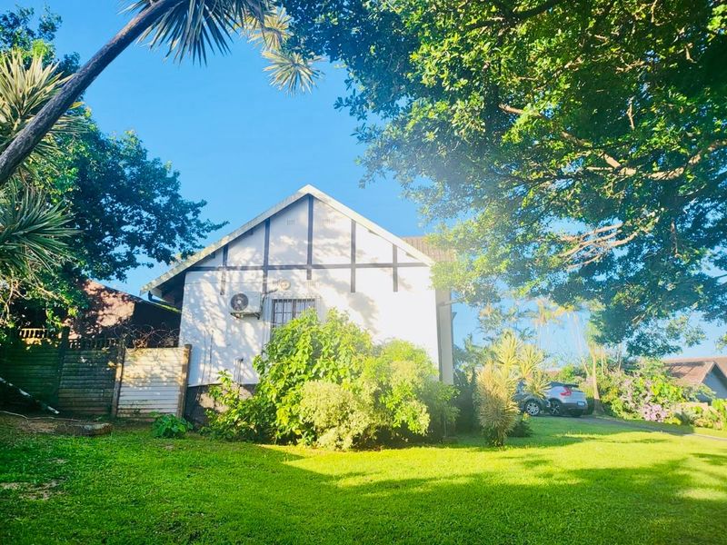 A view of the front facade of the house featuring timber-framed detailing, security bars on windows, and an external air conditioning unit.