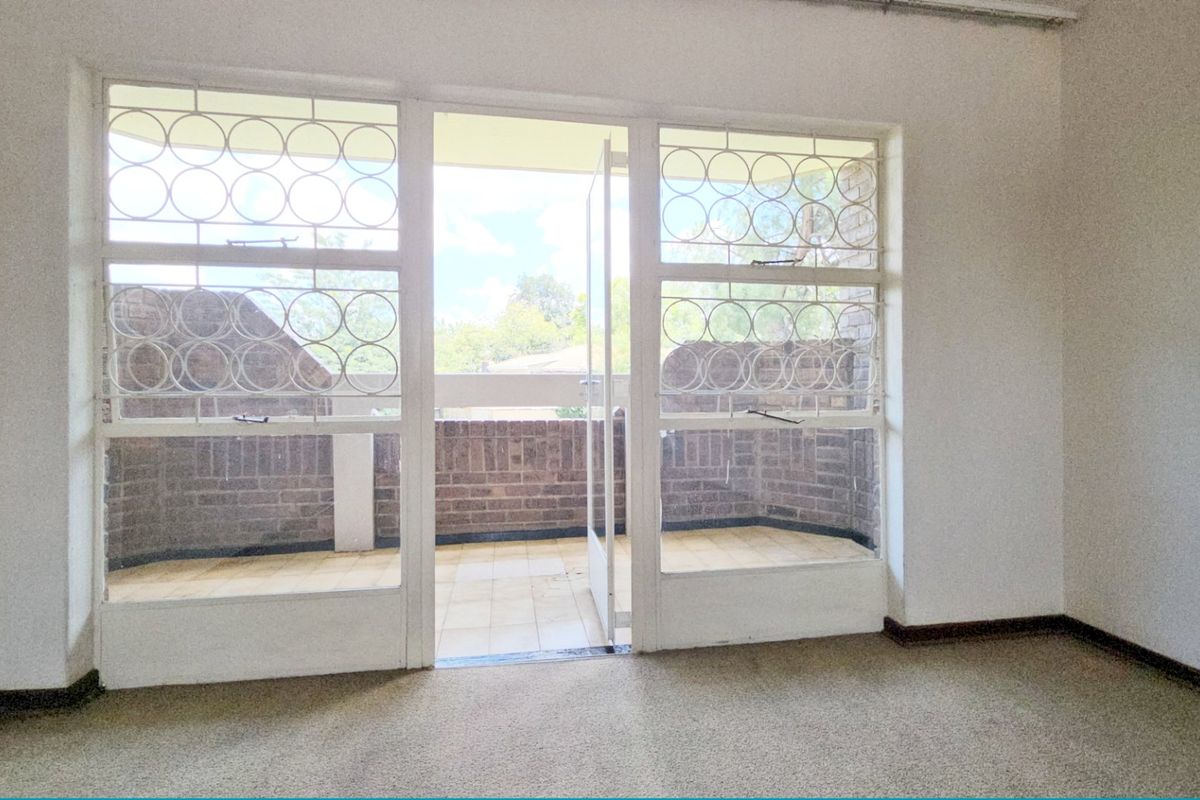 An empty bedroom featuring carpeted flooring and direct access to a private balcony through a secure door.