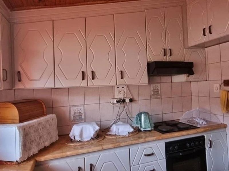 A functional kitchen featuring built-in cabinetry, tiled backsplash, and integrated cooking appliances, including an oven and hob, with a warm wooden ceiling finish.