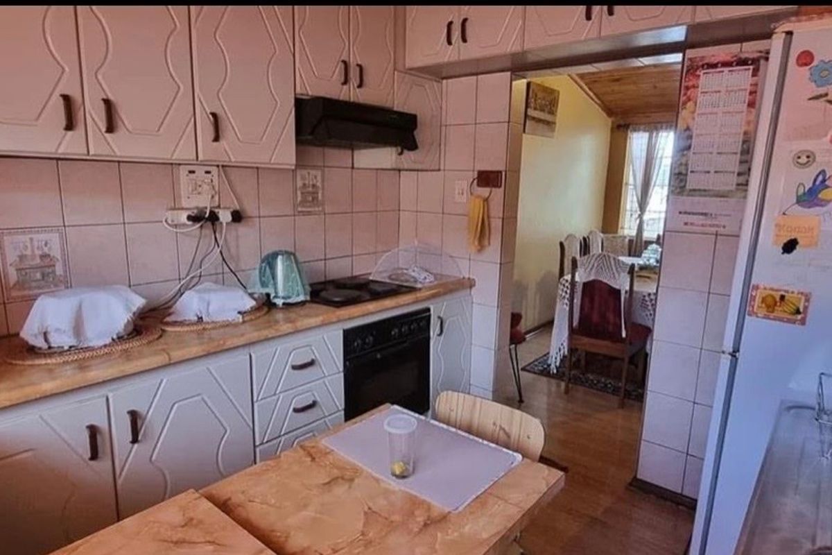 A functional kitchen featuring dated cabinetry, tiled backsplash, and built-in cooking appliances, with an open flow into the adjacent dining area.