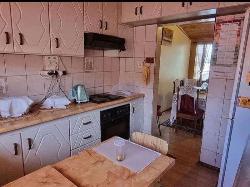 A functional kitchen featuring dated cabinetry, tiled backsplash, and built-in cooking appliances, with an open flow into the adjacent dining area.