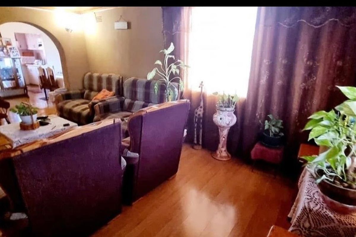 A living room featuring laminate flooring and an arched doorway leading to an adjacent space, providing a traditional layout.