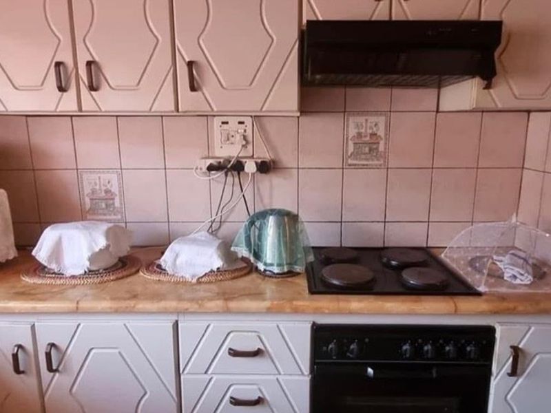 A functional kitchen featuring built-in cabinetry, a tiled backsplash, an electric hob, and an integrated oven with an overhead extractor fan.