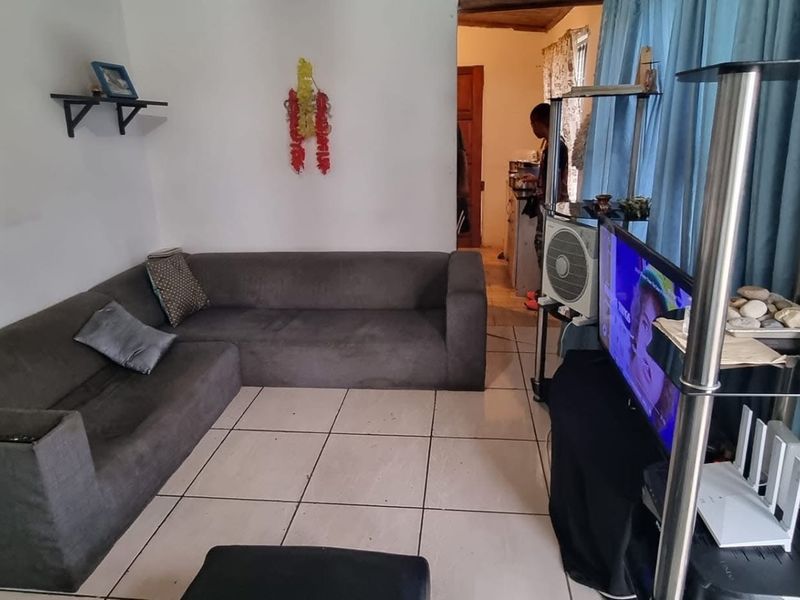 A living room area featuring tiled flooring and an installed air conditioning unit, showing signs of wear on the walls.